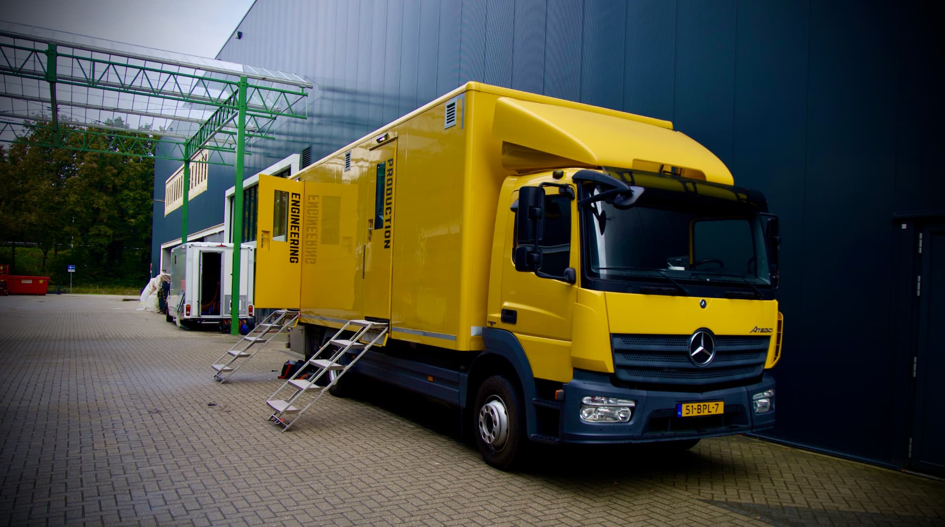 Gele Transvision Support regiewagen buiten aan een hal