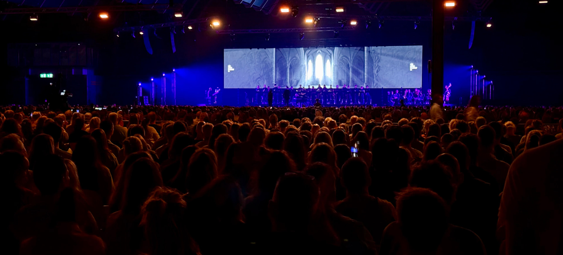 Koor en orkest in blauw verlichte zaal